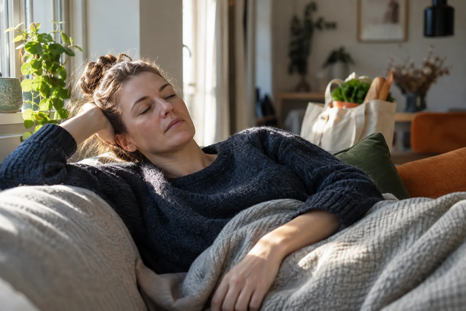 Een persoon rust op een bank met daglicht op het gezicht; een boodschappentas van een eerdere activiteit staat op de achtergrond.